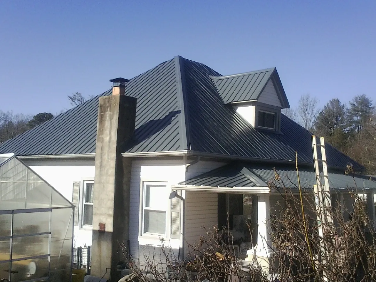 Dark blue standing seam metal roof on a white farmhouse with dormer — Slate & Tile Roof Repair by Roofing Brothers in Nahant