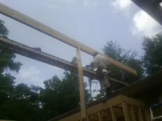 Carpenter setting a ridge beam over a new addition frame — Ice Dam Removal by Roofing Brothers in Nahant