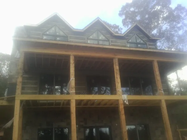 Dormers and porch framing on a large log home under construction — Roof Coating work by our crew in Nahant