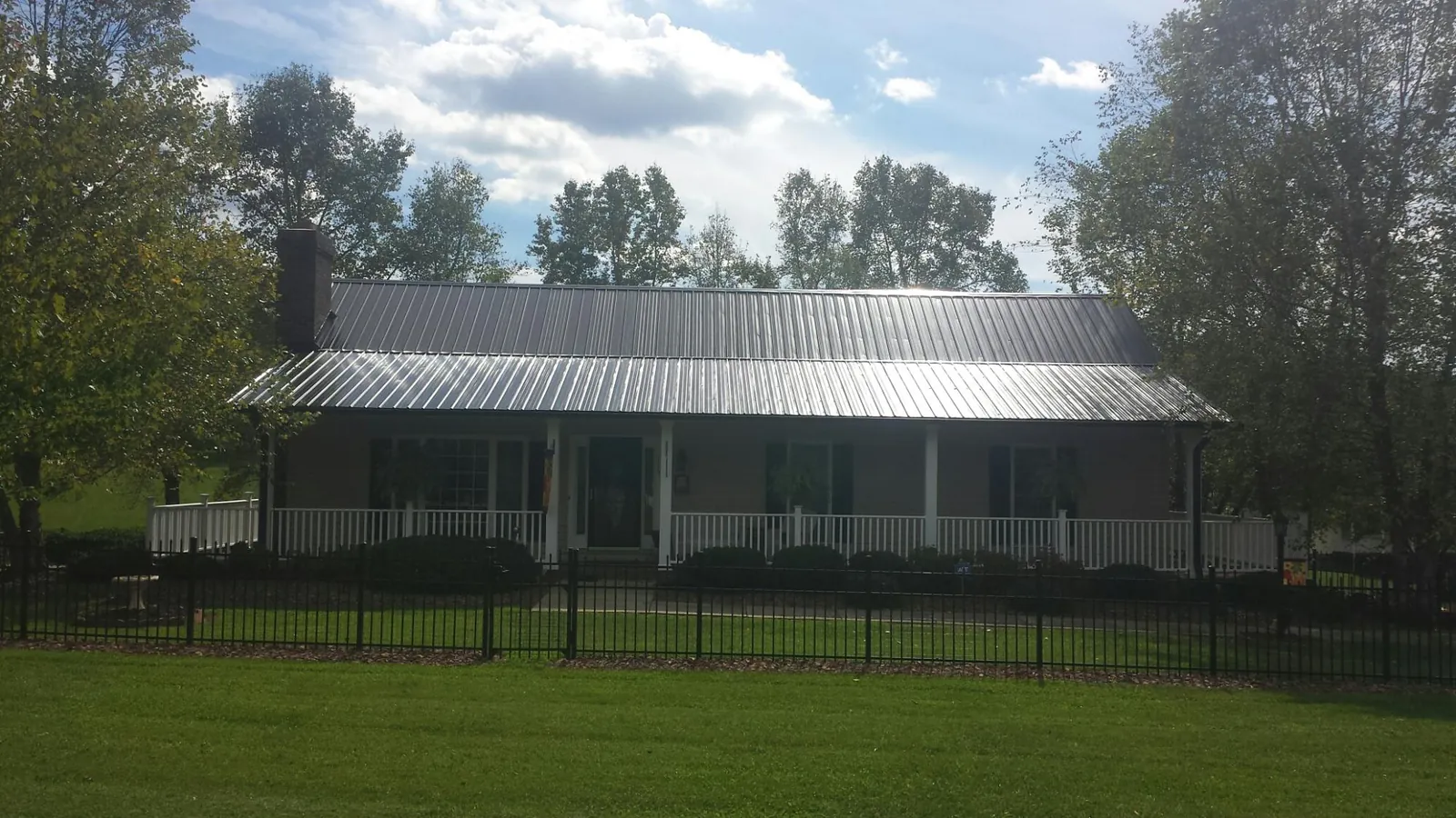 Gray metal roof on a brick ranch with a full width front porch — Gutter Guard Installation work by our crew in Nahant