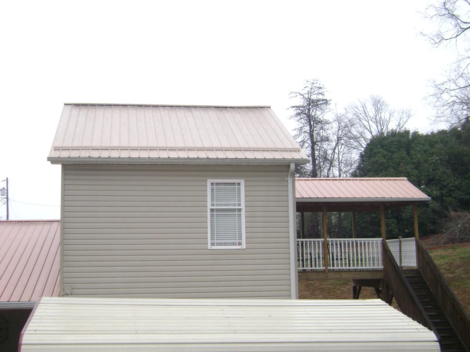 Tan metal roofs on a two story addition and attached porch, from a Roof Replacement job in Nahant