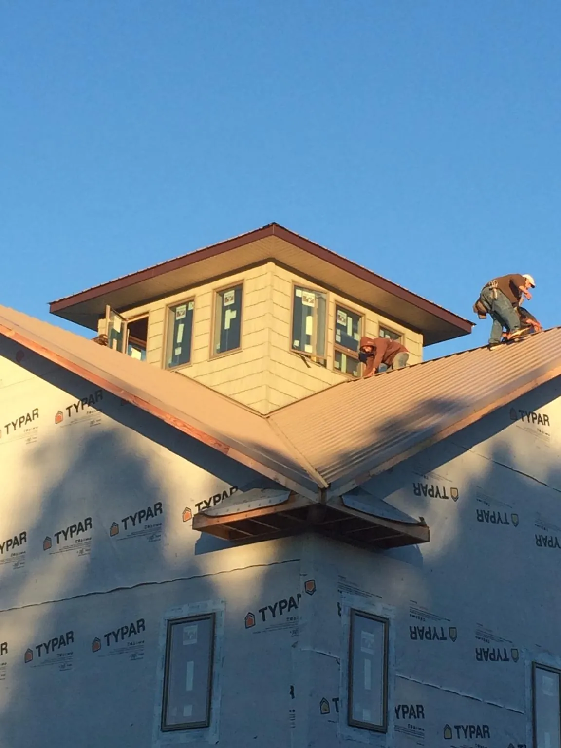 Roofers working around a rooftop cupola on a new metal roof at sunset — Roof Waterproofing in Nahant by Roofing Brothers
